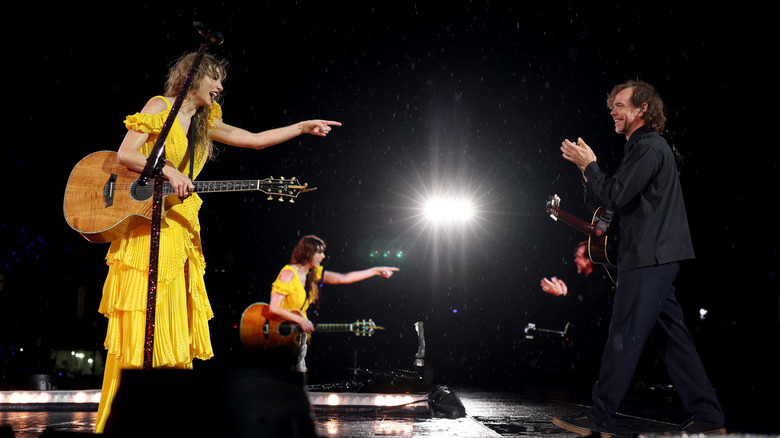 Taylor Swift playing guitar on stage with Aaron Dessner