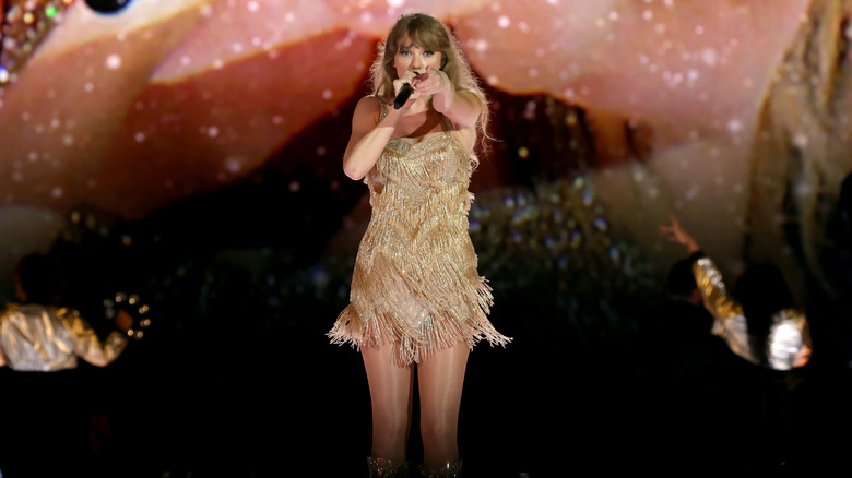 Taylor Swift performing on stage in gold dress