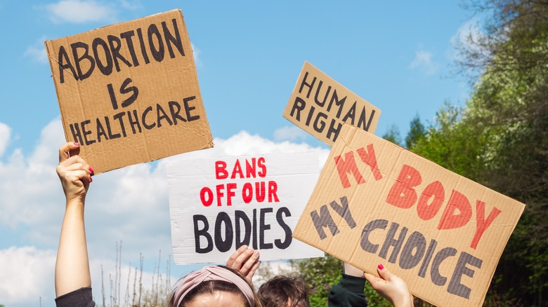 people hold signs in support of woman's reproductive rights