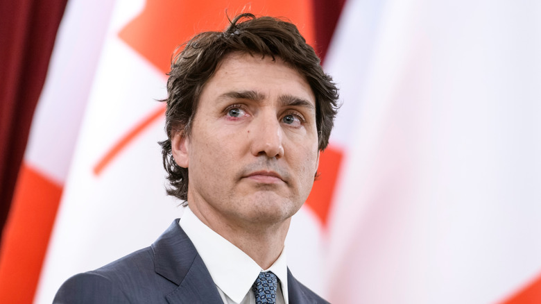 Justin Trudeau stands in front of the Canadian flag