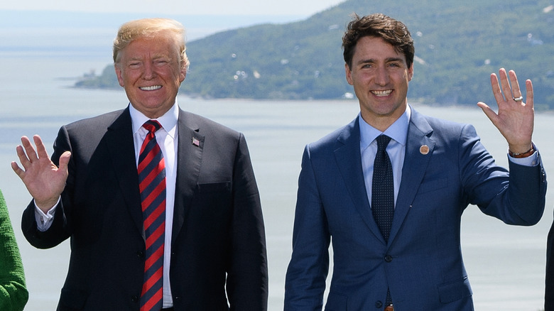 Donald Trump and Justin Trudeau smiling and waving awkwardly in suits