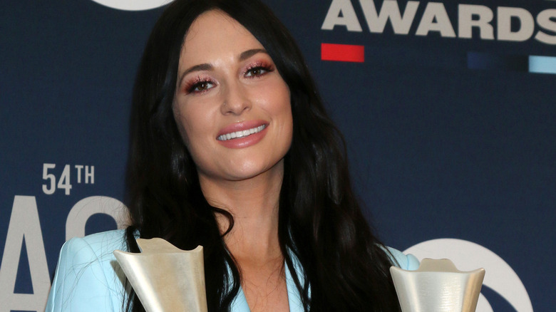 Kacey Musgraves holding two awards