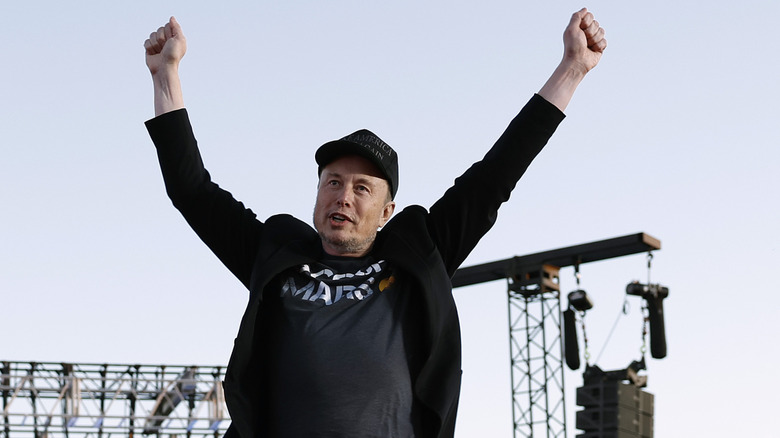 Elon Musk with his hands in the air