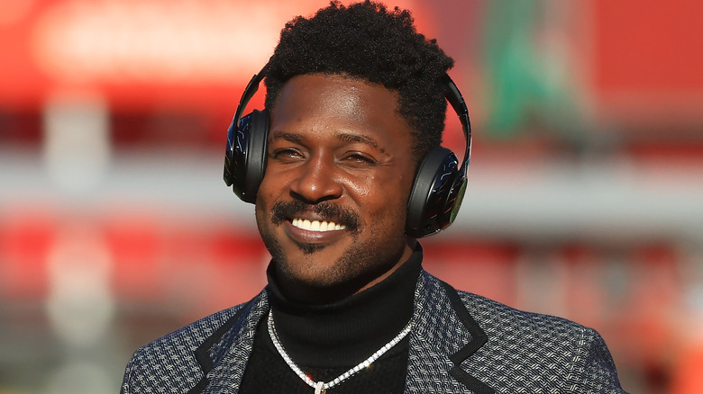 Antonio Brown wearing a suit and headphones smiling