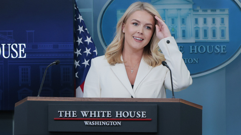 Karoline Leavitt brushing her hair back from her face during a press briefing in April 2025