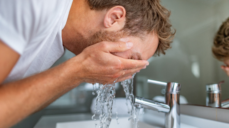 Man splashing water on his face in bathroom