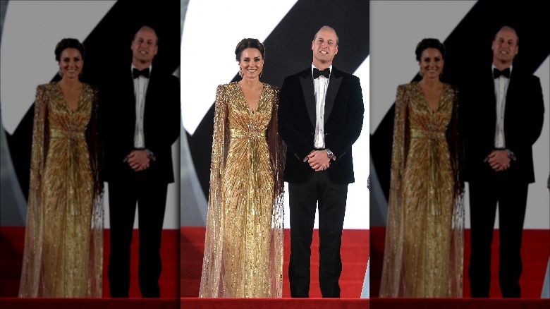 Kate Middleton wearing sparkly gold gown next to Prince William wearing a black tux on No Time To Die red carpet.