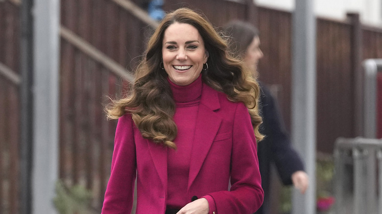 Kate Middleton with wide smile in a fuchsia top and fresh blowout 