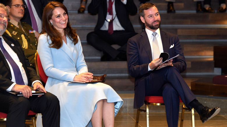 Kate Middleton sitting, wearing blue coat