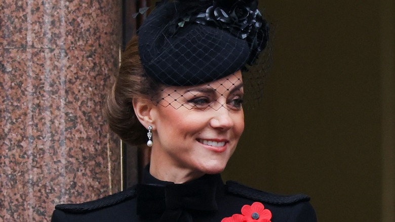 Kate Middleton smiling while wearing a black fascinator