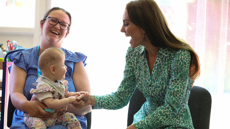 Princess Catherine smiling and shaking a baby's hand