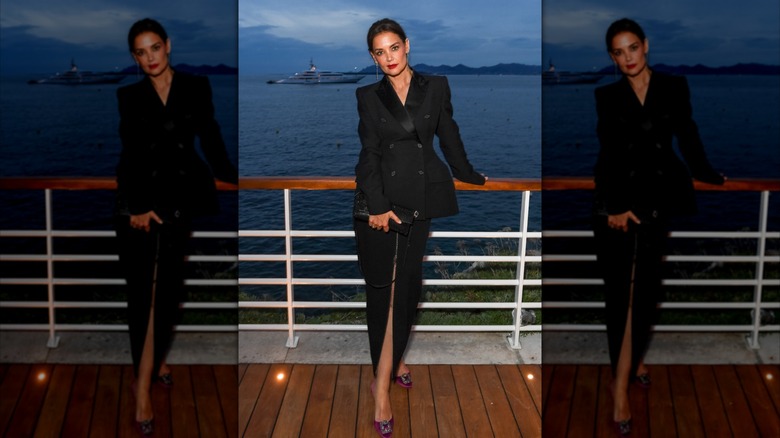 Katie Holmes posing on a boat in a black blazer and long black skirt