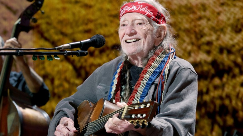 Willie Nelson smiling while playing guitar