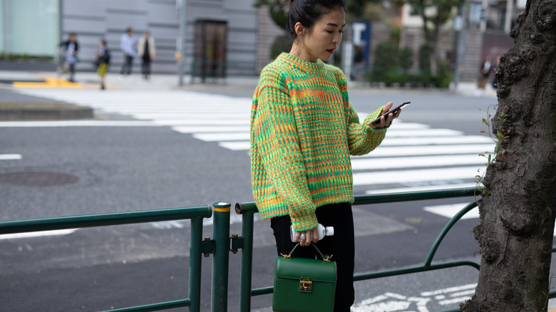 woman holding purse wearing colorful knit