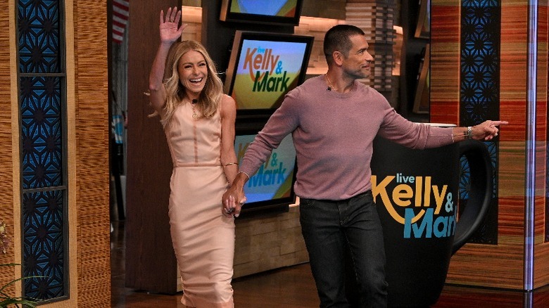 Kelly Ripa and Mark Consuelos waving on the set of Live with Kelly and Mark