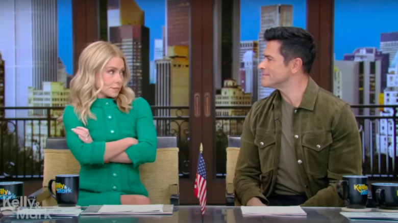 Kelly Ripa folding her arms while looking at Mark Consuelos