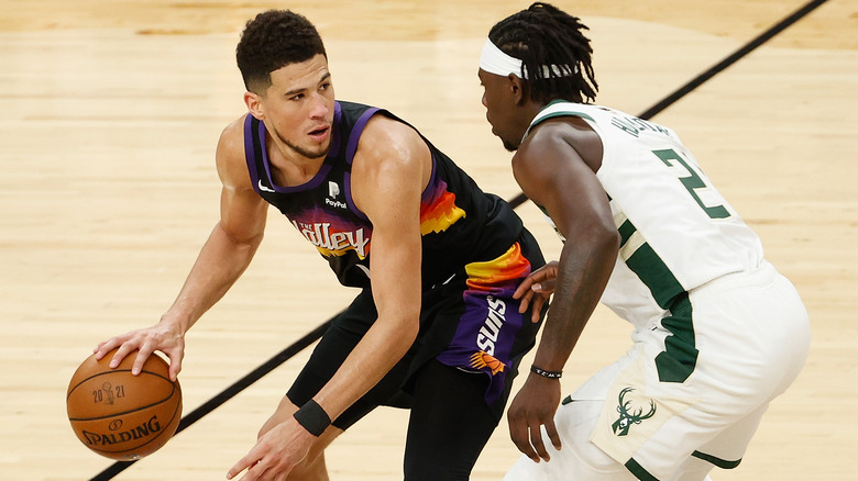 Devin Booker of the Phoenix Suns handles the ball against Jrue Holiday