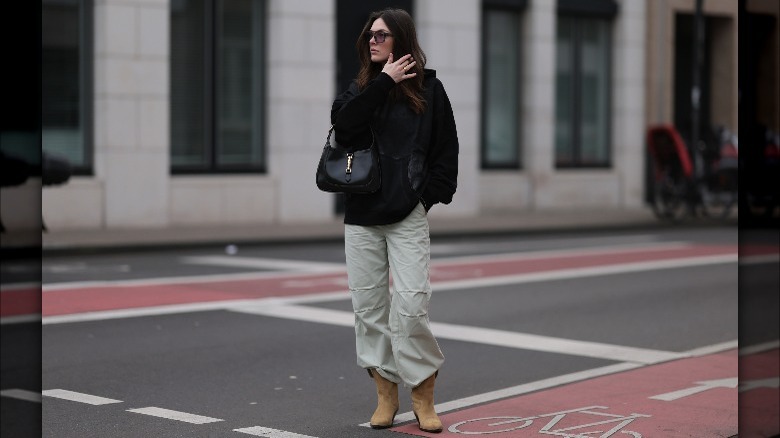 Woman in black coat and tan cargo pants