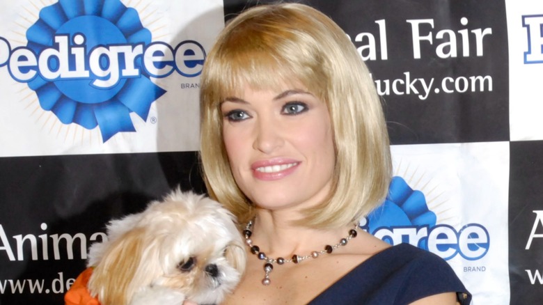 Kimberly Guilfoyle in blond wig, holding a dog