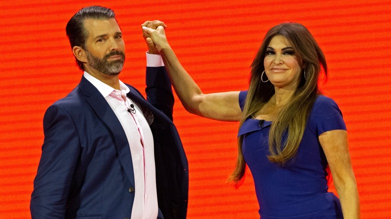 Donald Trump Jr. and Kimberly Guilfoyle with hands awkwardly intertwined on stage