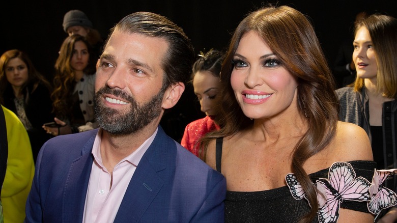 Donald Trump Jr. and Kimberly Guilfoyle sitting next to each other smiling