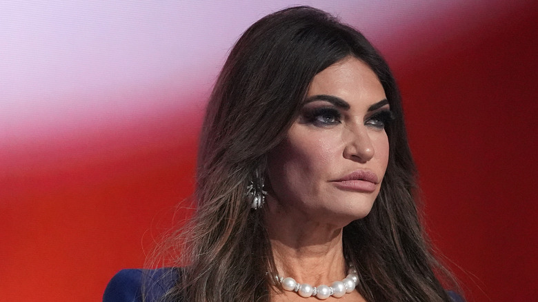 Kimberly Guilfoyle staring with dark eye makeup and large pearl necklace