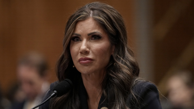 Kristi Noem stands in front of a microphone