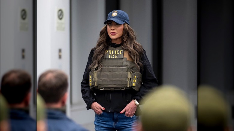 Kristi Noem wearing ICE vest and ball cap looking serious