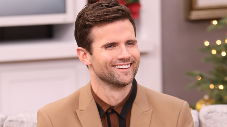 Kyle Dean Massey smiling on couch