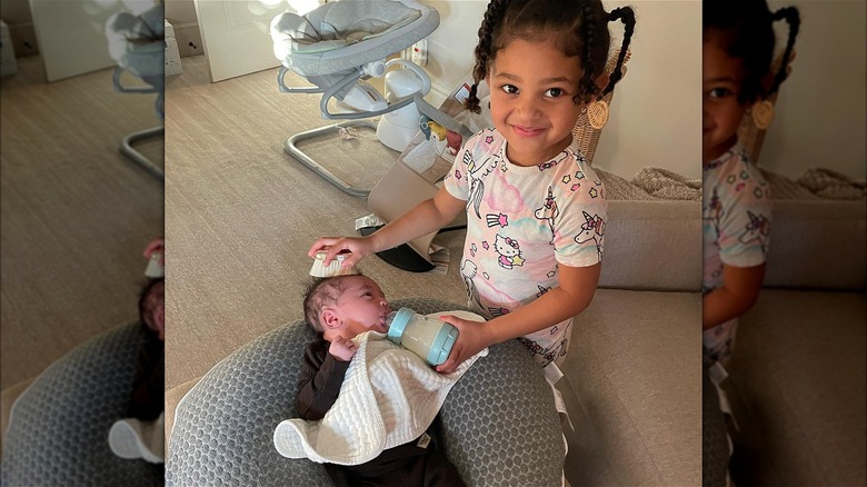 Stormi feeding her baby brother Aire