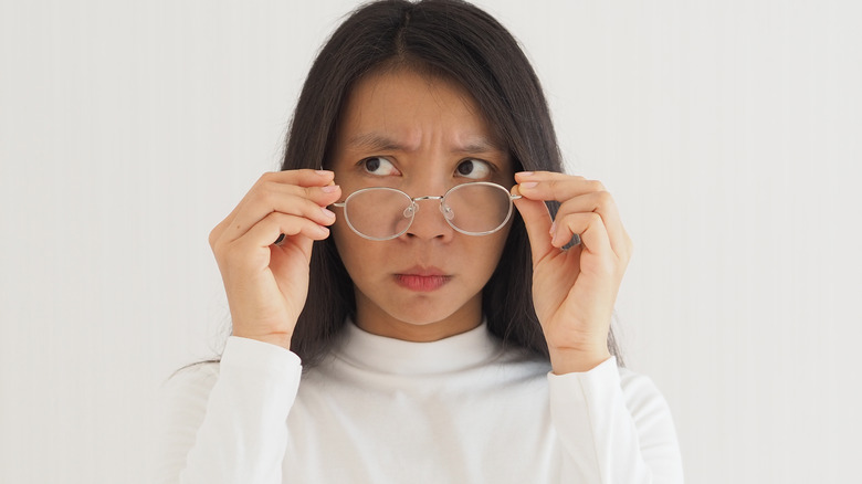 Woman putting on glasses