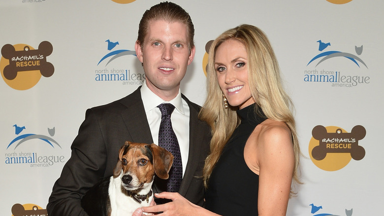 Eric Trump and Lara Trump smile while holding their rescue dog