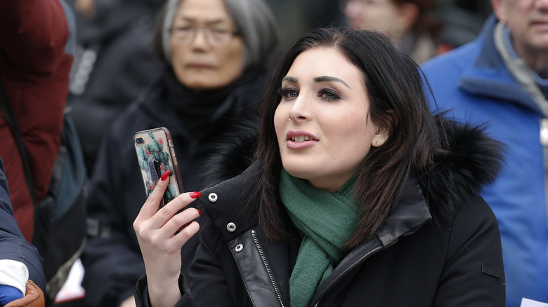 Laura Loomer holding her phone