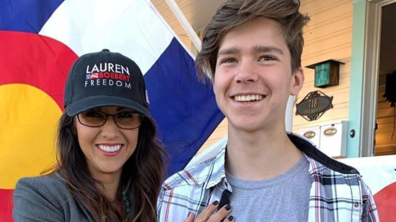 Tyler Boebert and Lauren Boebert pose in front of a flag