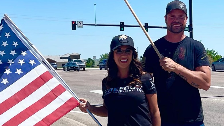 Lauren and Jayson Boebert pose with flags on sidewalk