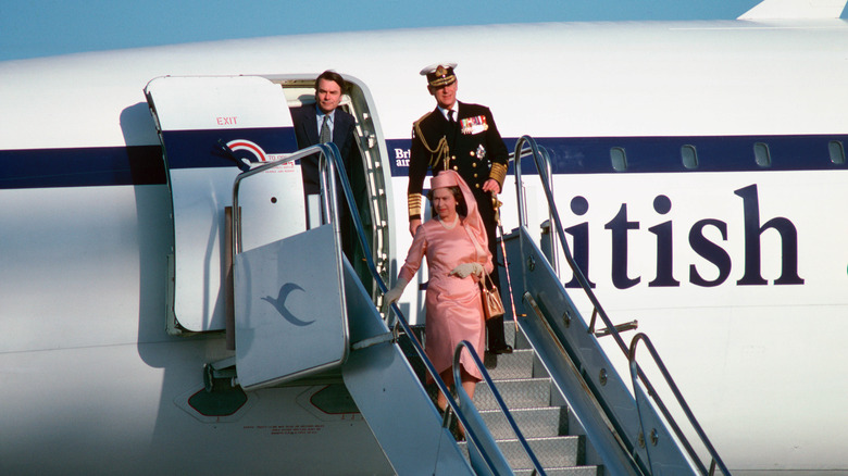 Queen Elizabeth and Prince Philip walking down the stairs of a British Airways plane