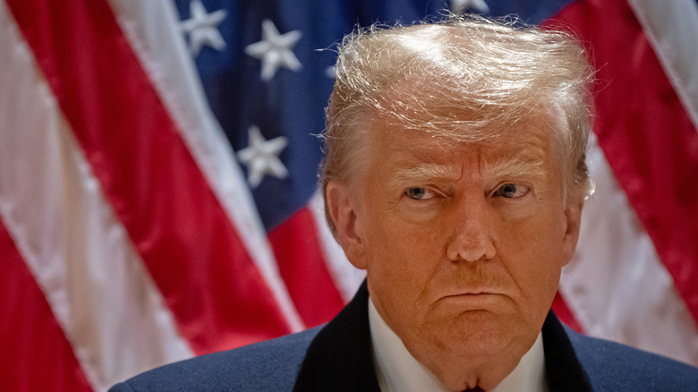 Donald Trump frowning in close-up near flag