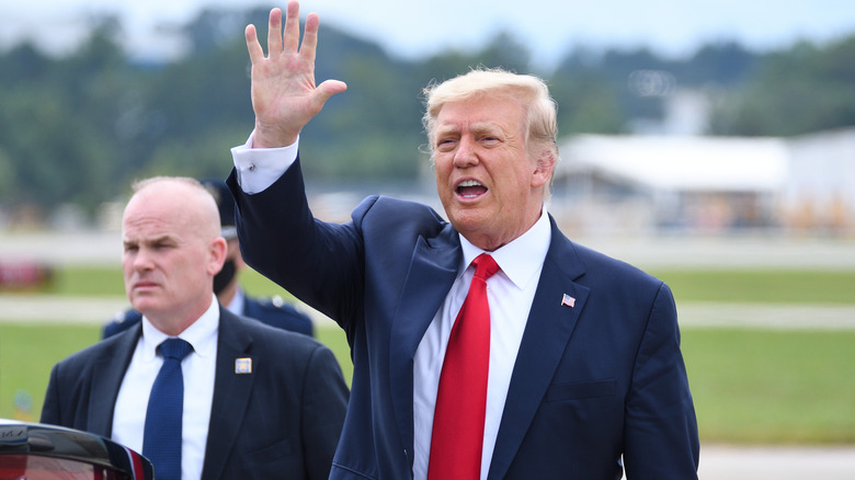 Donald Trump waving at crowds with Secret Service next to him