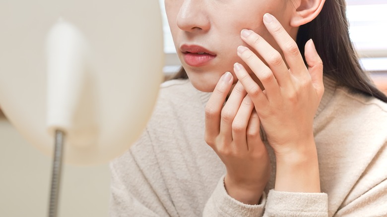 A woman examining her face