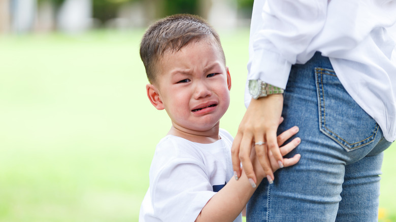 A boy crying next to his mother's midsection