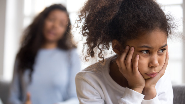 An upset kid with mother in the background