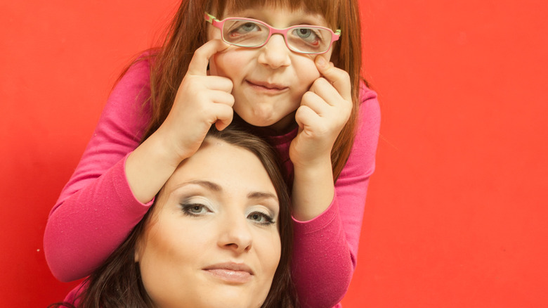 A girl making a silly face and her mother