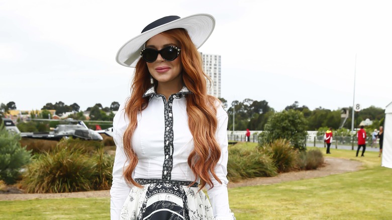 Lindsay Lohan smiling in all white, black sunglasses