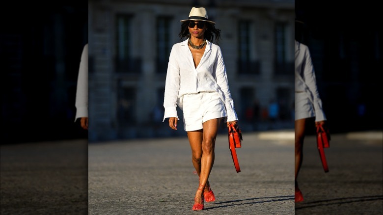 Woman wearing all-white linen outfit with red accessories