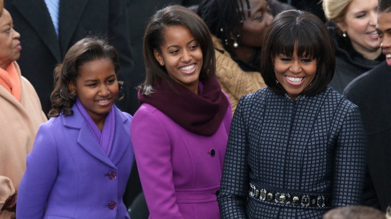 Sasha and Malia Obama standing next to Michelle Obama