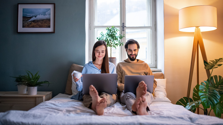 couple working on laptops in bed