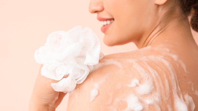 Woman bathing with a white loofah