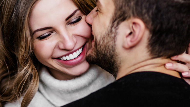 Couple hugging and man kisses woman on cheek