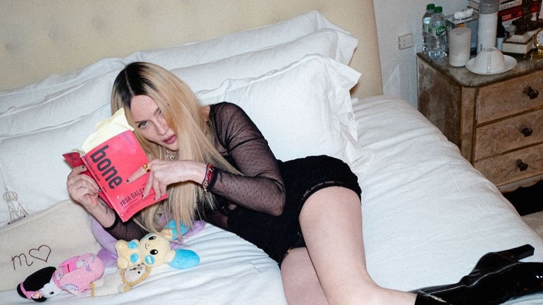 Madonna reading in bed with stuffed animals