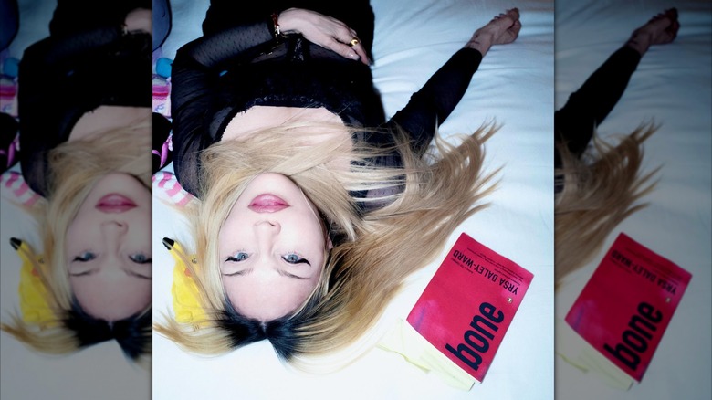 Madonna lying on a bed looking serious with a book